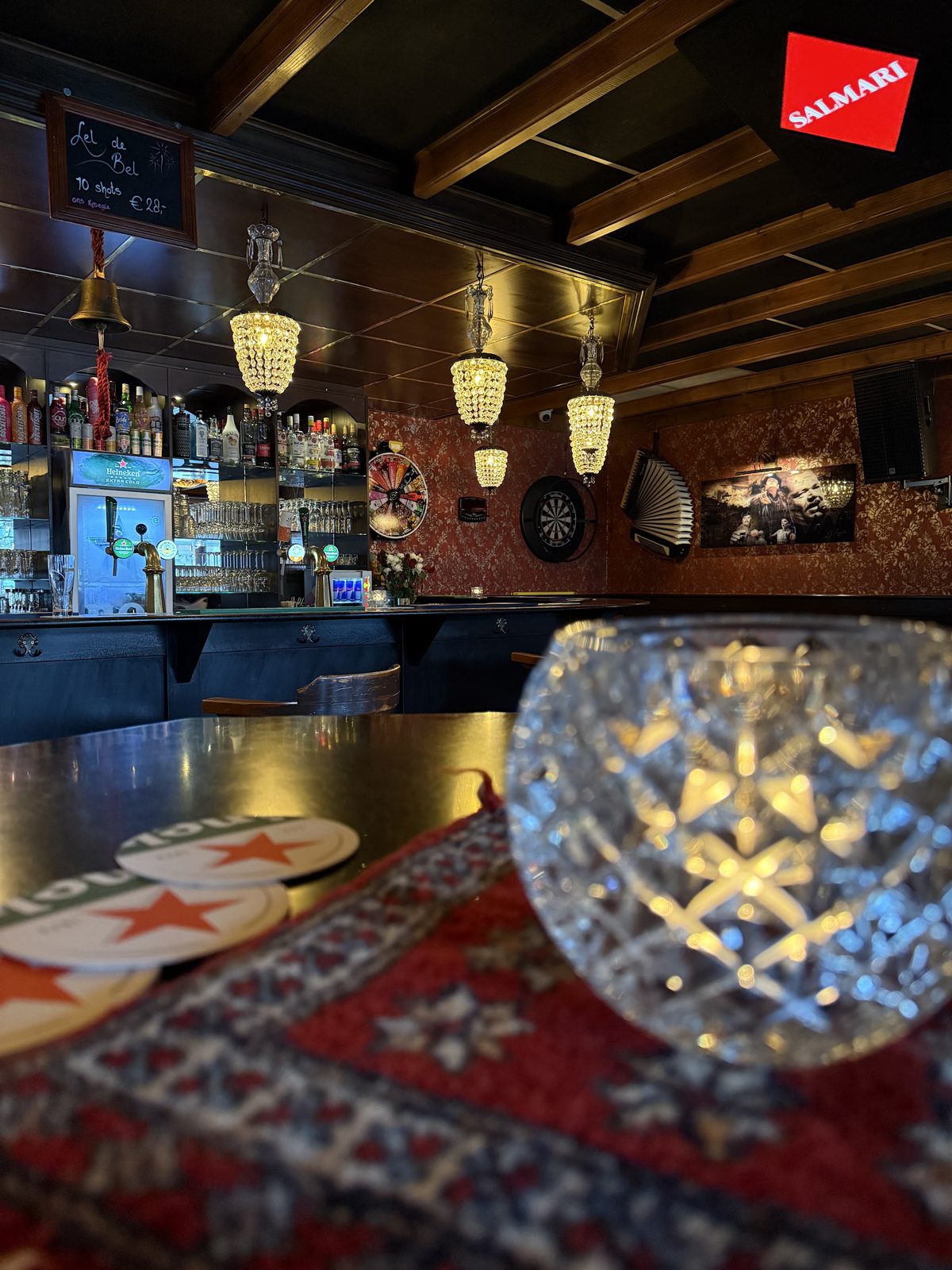 De bar van binnen, met kroonluchters, donker hout en een Perzisch tapijt
